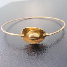 "Cowboy Hat Bracelet - Cowgirl Hat Bracelet - Southwestern Jewelry - A brass cowboy hat charm has been transformed into a cool & dainty cowgirl bangle bracelet with a gold tone brass band for you to wear. I can also make this cowgirl or cowboy bangle bracelet with a 14k gold filled bangle band for $10 more. If you would like this option for your cowgirl bracelet, select from options when ordering. This cowboy bracelet stacks great together with other bangles from my collection as you can see Country Girl Jewelry, Cowgirl Bracelets, Cowboy Jewelry, Western Bracelets, Cowgirl Gifts, Bracelet Stacks, Cowgirl Jewelry, Cowgirl Hat, Southwest Jewelry