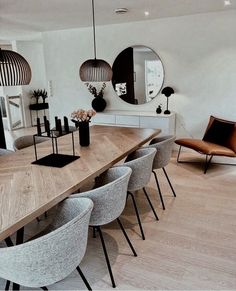 a dining room table with chairs and mirrors on the wall above it, in front of a mirror