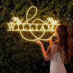 a woman holding up a neon sign that says mr and mrs william