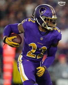 a football player running with the ball in his hand and wearing purple uniform, during a game