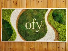 a moss covered wall with the word oy written in white letters on top of it