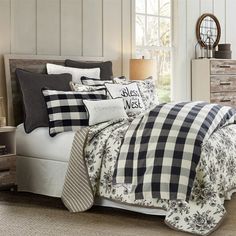 a bed with black and white comforters in a room next to a dresser filled with drawers