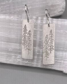 "Large sterling silver Tall Pine Earrings etched with Lodge Pole Pines. The earrings dangle from sterling silver French wires and measure 1 1/8\" x 3/8\"." Silver Etched Earrings As A Gift, Silver Stamped Earrings For Everyday, Silver Etched Earrings For Gifts, Everyday Silver Stamped Earrings, Elegant Stamped Earrings As Gift, Engraved Sterling Silver Adjustable Earrings, Etched Sterling Silver Dangle Earrings, Silver Etched Dangle Jewelry, Dangle Etched Earrings As Gift