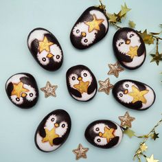 six penguins painted on rocks with gold stars