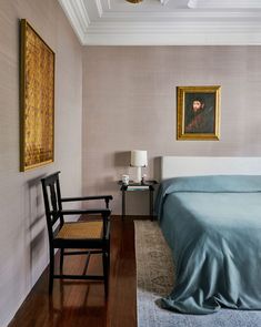 a bedroom with a bed, chair and painting on the wall in it's corner