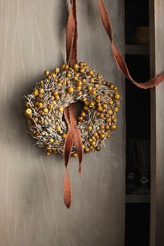 a wreath hanging on the side of a door next to a wine glass and ribbon