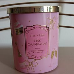 a pink candle that is sitting on a table next to a cup with gold trimmings