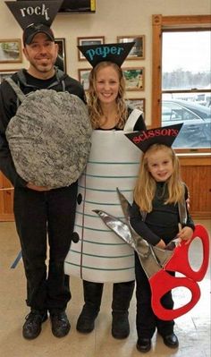 two adults and one child are dressed up as doctor who is holding a giant pair of scissors