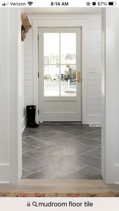 an open door leading into a room with white walls and gray tile flooring on either side