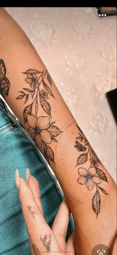 a woman's arm with flowers and butterflies tattooed on the side of her arm