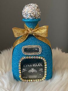 a blue bottle with a gold bow around it and some jewels on the top is sitting on a white fur