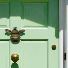 a green door with a brass bee handle on it