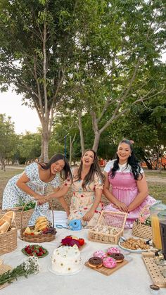 three girls are standing around a table with food on it and one girl is smiling at the camera