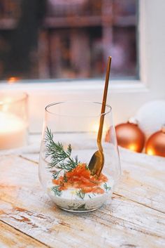 a wooden table topped with a glass bowl filled with food and a spoon sticking out of it