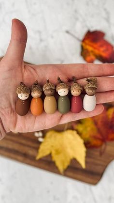 a person's hand holding five small wooden figurines