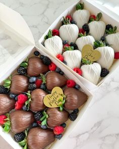 two boxes filled with chocolate covered strawberries and raspberries