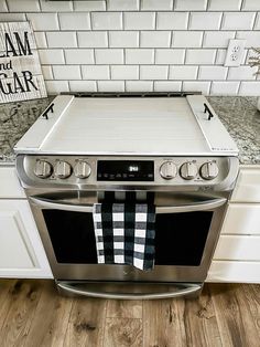 a stove top oven sitting in a kitchen next to a white tiled wall and wooden floor