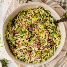 a white bowl filled with shredded cabbage and chickpeas on top of a table