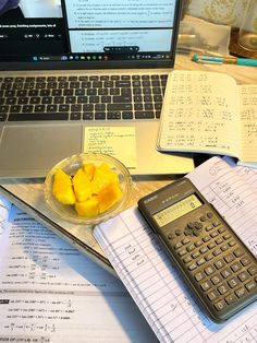 a laptop computer sitting on top of a desk next to a calculator and notebook