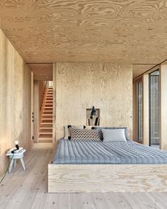 a bed sitting in the middle of a bedroom next to a wooden wall and stairs