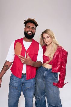 the man and woman are posing together for a photo in their red vests, white t - shirt and blue jeans