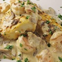 a white plate topped with chicken and potatoes covered in gravy, garnished with parsley