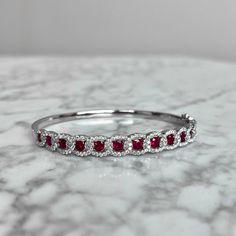 This elegant ruby and diamond bangle bracelet is crafted from 18K white gold and boasts 106 natural diamonds and 13 rubies of superior (G) color and (VS2) clarity for a total of 4.17CTW. Brilliantly cut and carefully prong set, this bracelet adds timeless sophistication to any ensemble. Luxury Ruby Bracelets Elegant Style, Luxury Ruby Bangle, Red Diamond Fine Jewelry Bracelet, Red Diamond Bracelets Fine Jewelry, Red Diamond Tennis Bracelet For Weddings, Red Diamond Bracelet Fine Jewelry, Red Diamond Oval Bracelet, Red Diamond Bracelet In Fine Jewelry Style, Red Diamond Bracelet For Wedding