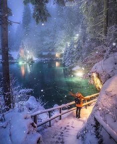 a person is standing on a bridge over a lake in the snow with their arms outstretched