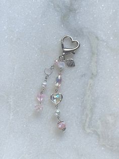 a keychain with hearts and beads on it sitting on a marble surface in the snow