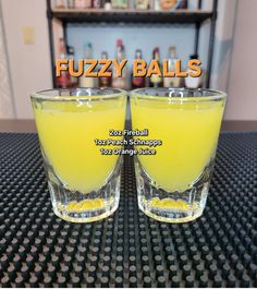 two glasses filled with yellow liquid sitting on top of a table