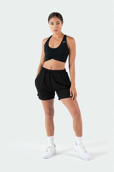 a woman in black sports bra top and shorts posing for the camera with her hands on her hips