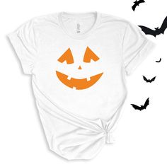 a white t - shirt with an orange jack o lantern face on it and bats flying around