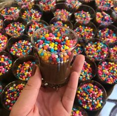 a hand holding a cup filled with chocolate and sprinkles