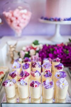 there are many flowers on the trays and candy in the vases next to each other