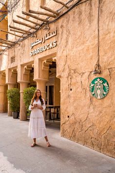 a woman standing in front of a starbucks sign