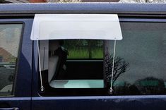 the back window of a blue car with white awnings and trees in the background