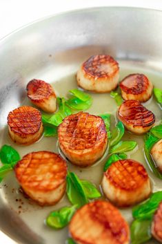 cooked scallops and spinach in a pan on a stove top with water