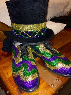 a pair of purple and green shoes sitting on top of a wooden table next to a black hat