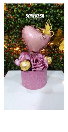 a pink cupcake topped with roses and a heart shaped balloon