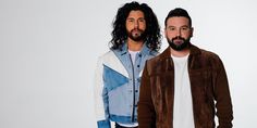 two men with long hair and beards standing next to each other in front of a white background