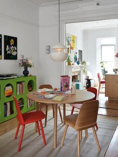 a dining room table with chairs and bookshelves in front of the door to an open living area