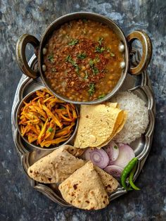 a metal plate topped with lots of food next to rice and tortilla chips