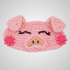 a pink crocheted pig head with flowers on it's ears and eyes