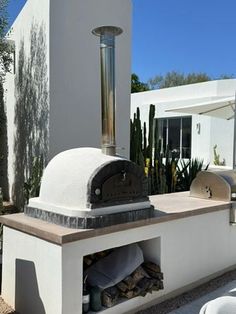 an outdoor pizza oven is built into the side of a house with cactus and cacti