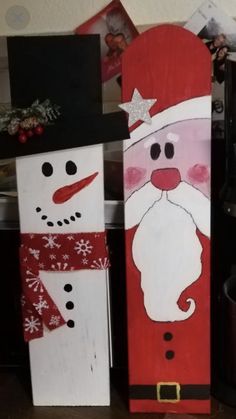 two snowmen made out of wooden boards with santa clause on one and a snowman on the other