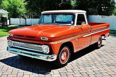 an orange and white truck parked on top of a brick road