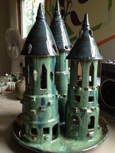 two green ceramic towers sitting on top of a table next to a fan and window