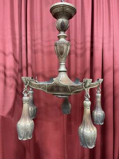 an ornate silver candle holder with four candles on it's sides and three hanging lights