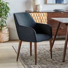 a blue chair sitting in front of a table with a vase on top of it