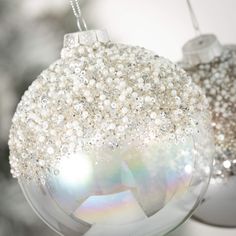 two white ornaments hanging from a tree with snow flakes on it's sides